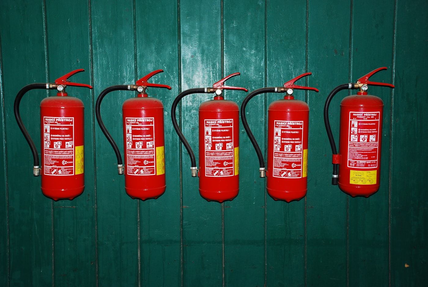 Row of serviced red fire extinguishers mounted on a wall
